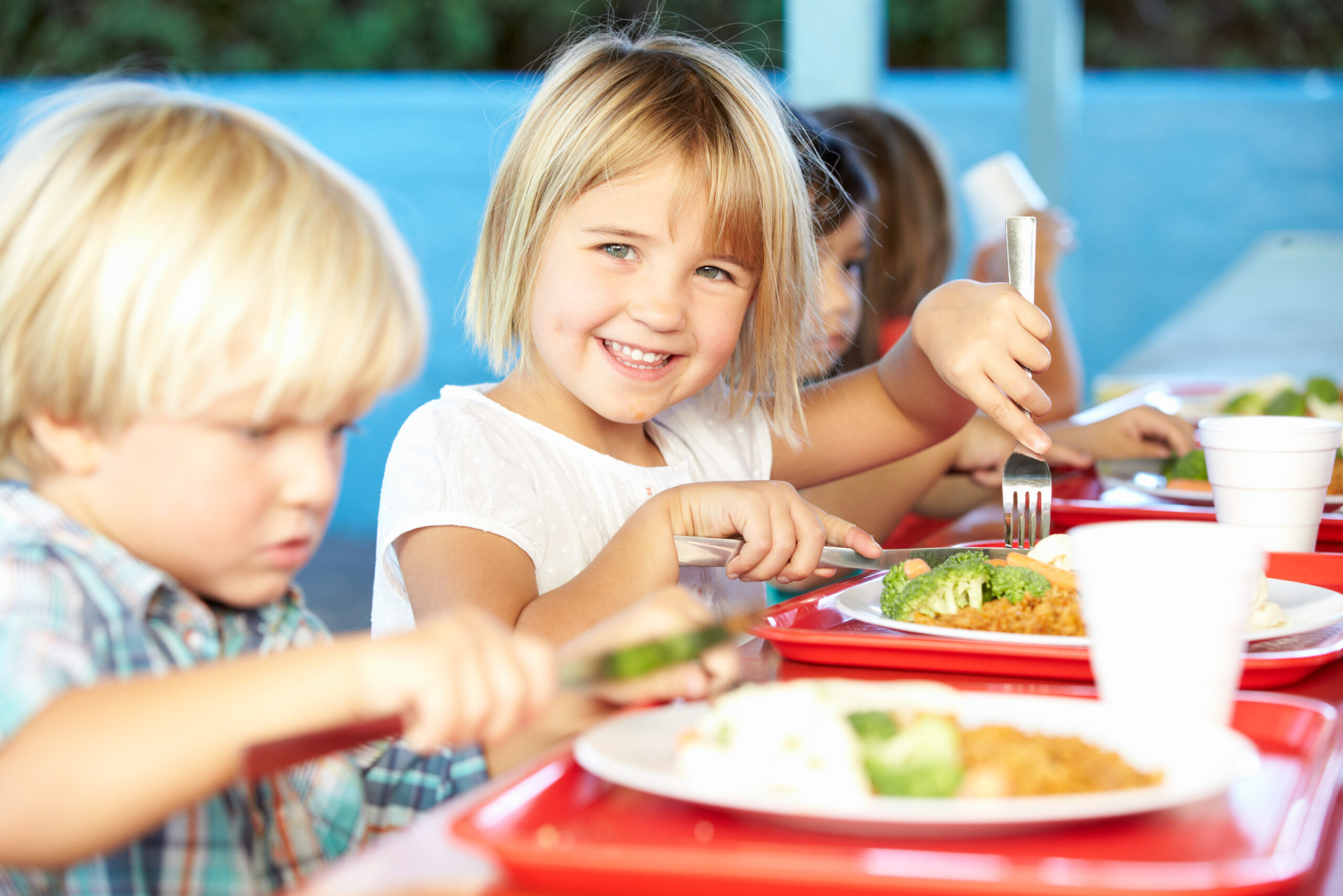 Young children smiling while eating a healthy lunch together